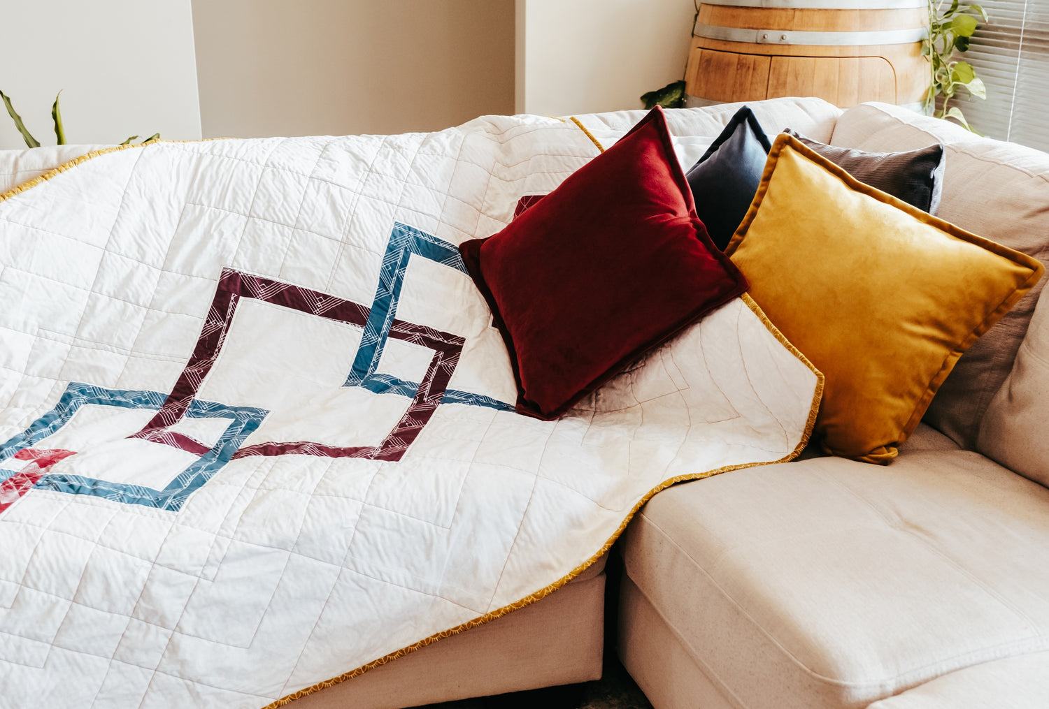 A handmade quilt is draped on a couch with matching colourful cushions