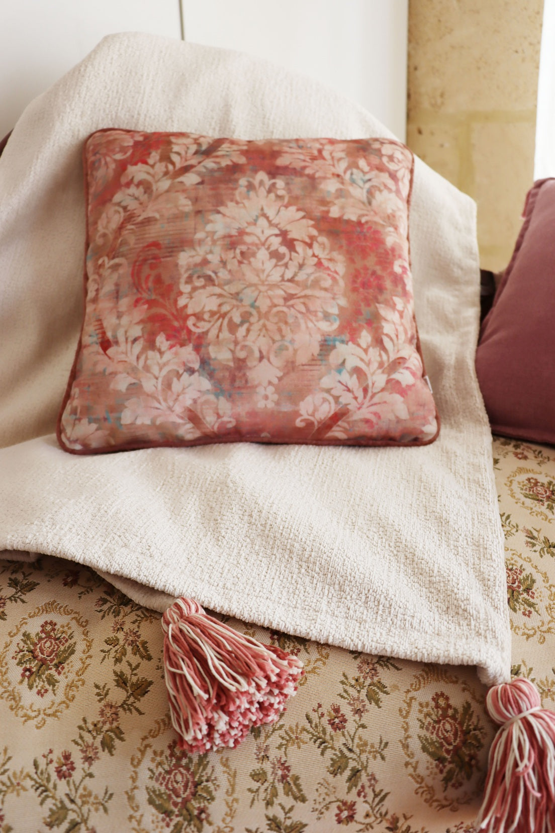 floral cushion cover with piped edge on a floral-patterned couch