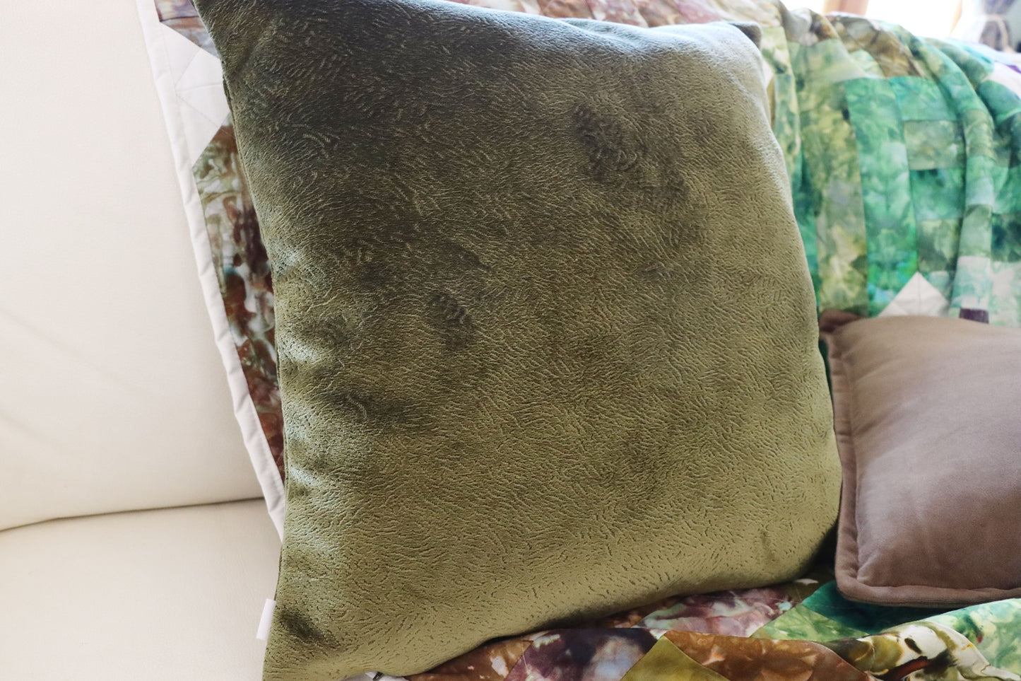 Green textured velvet cushion cover on a patterned sofa