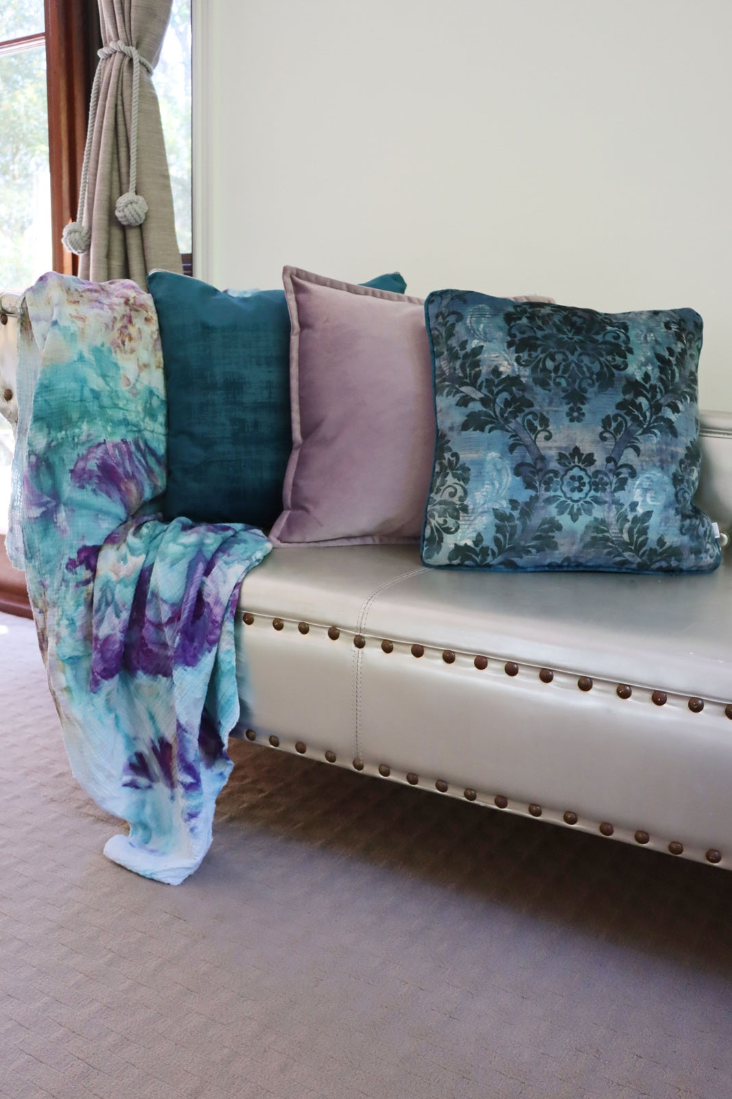 Blue floral cushion cover with piped edge and blanket on a sofa with a neutral background