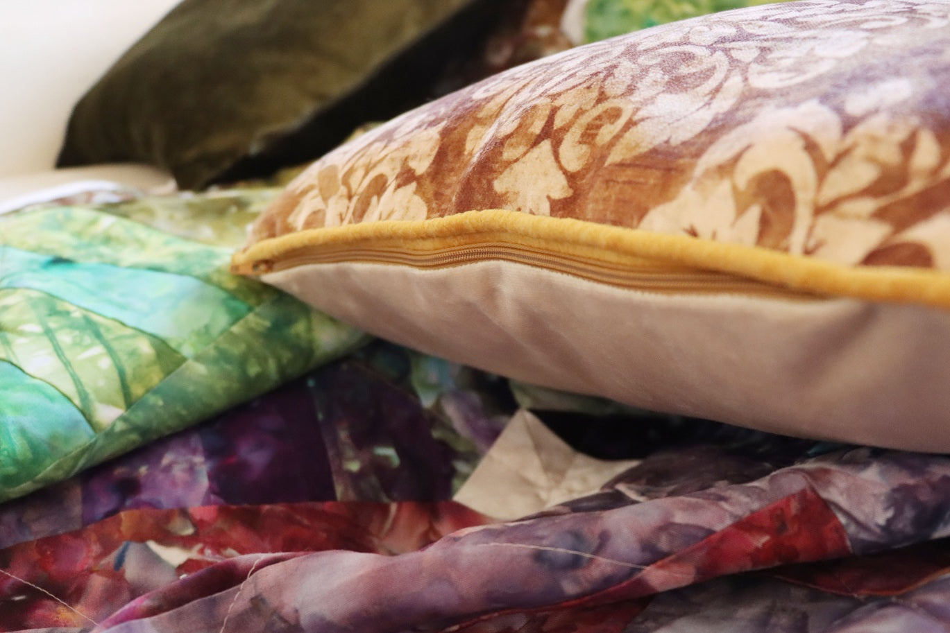 Close-up of a floral cushion cover with piped edge and quilt with a blurred background