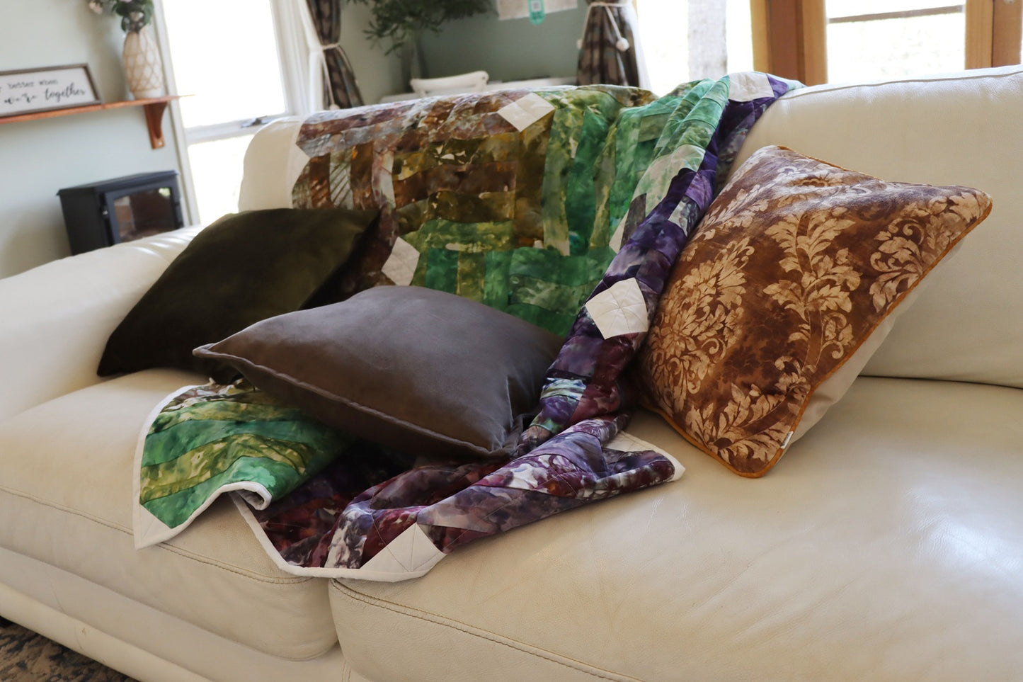 Colorful quilt draped over a beige sofa with floral cushion cover with piped edge