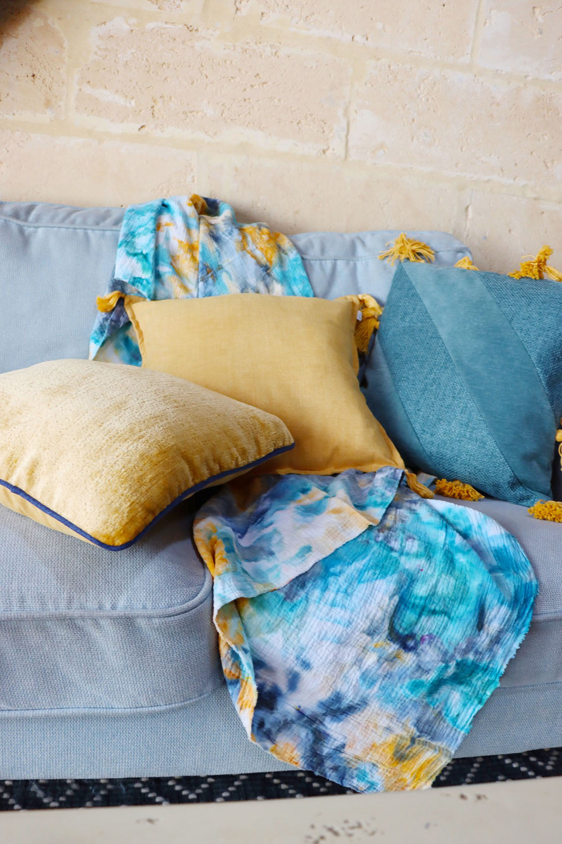 Decorative chenille cushion cover with contrasting piping on a sofa with a colourful blanket