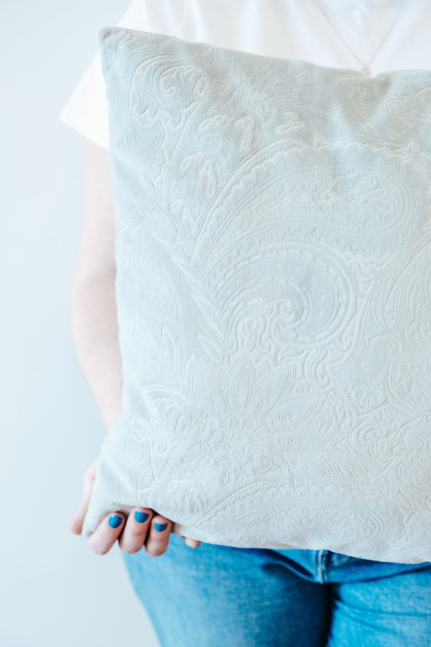 Close up of person holding a pale green textured velvet cushion cover