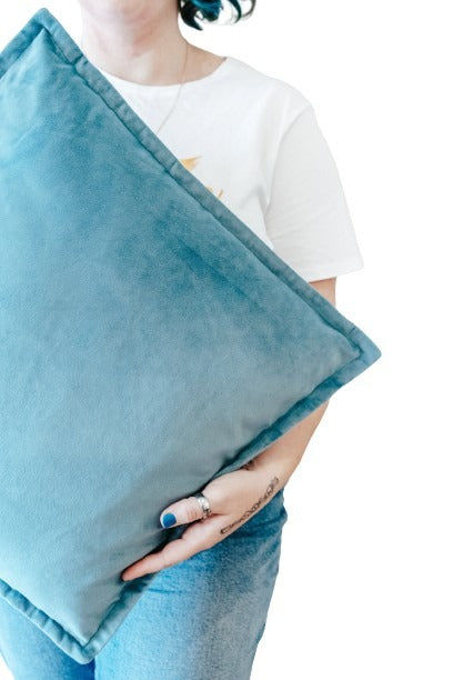 Close up person holding teal velvet cushion cover