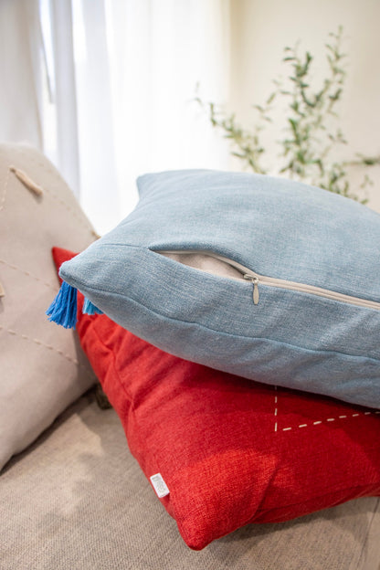 Back and zipper of blue, red and white cushion cover with embroidery and tassels on couch