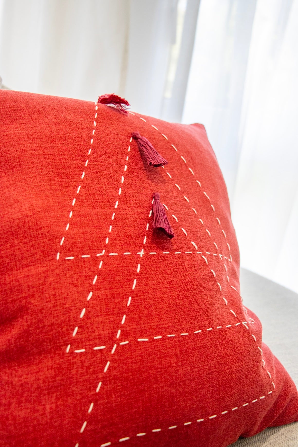 Close up of red triangle cushion cover with embroidery and tassels