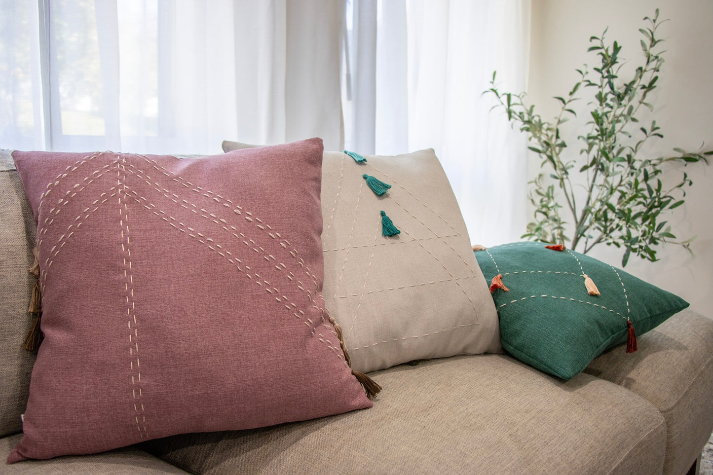 Pink, white and green cushion cover with embroidery and tassels on sofa