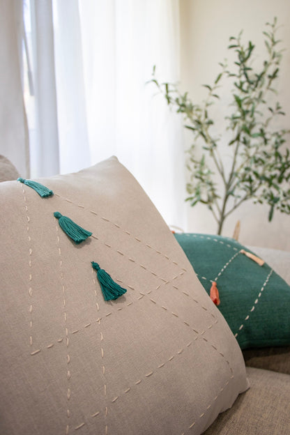 White and green cushion cover with embroidery and tassels on couch