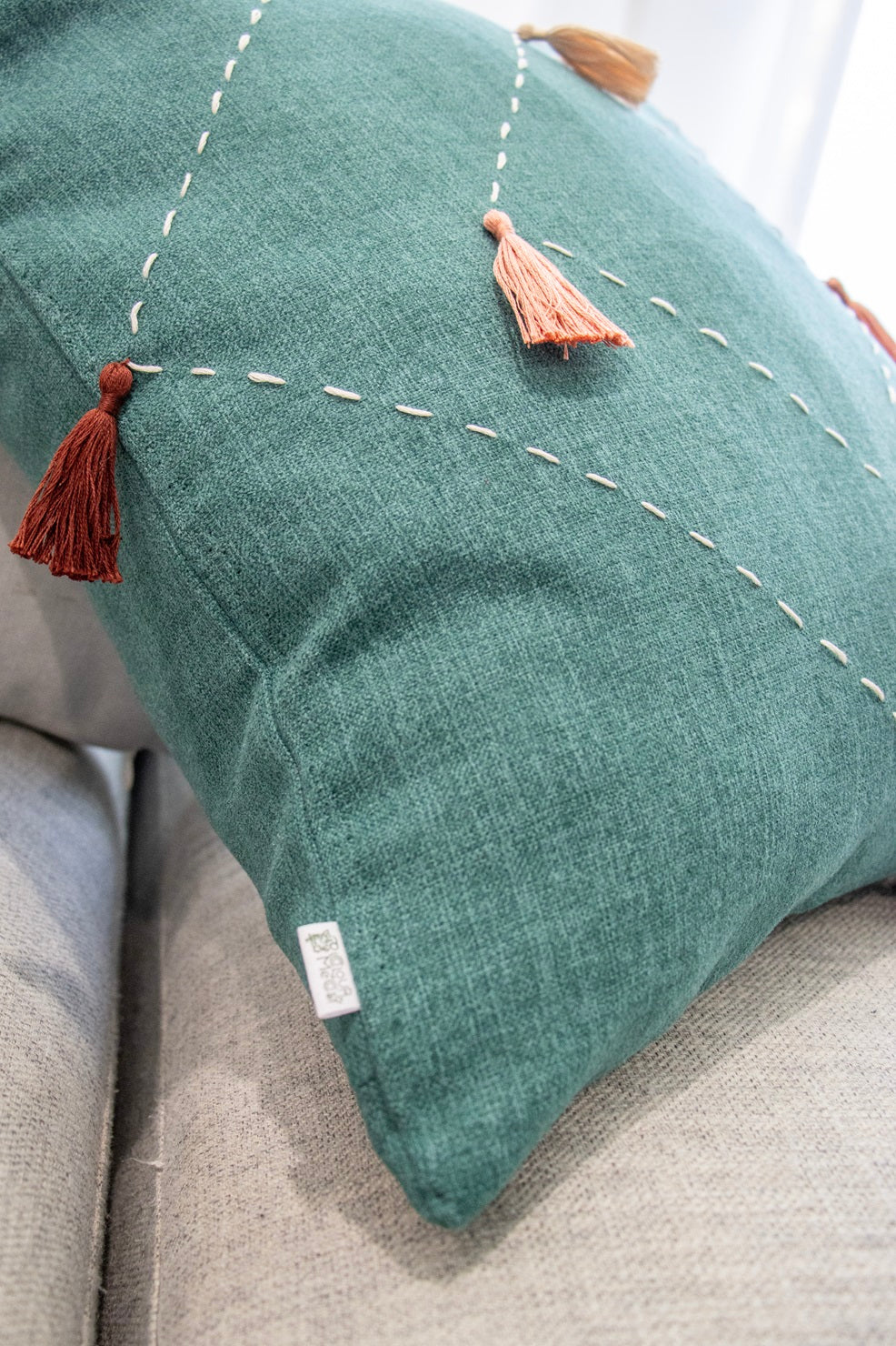 Close up of tag and tassels on cushion cover with embroidery and tassels