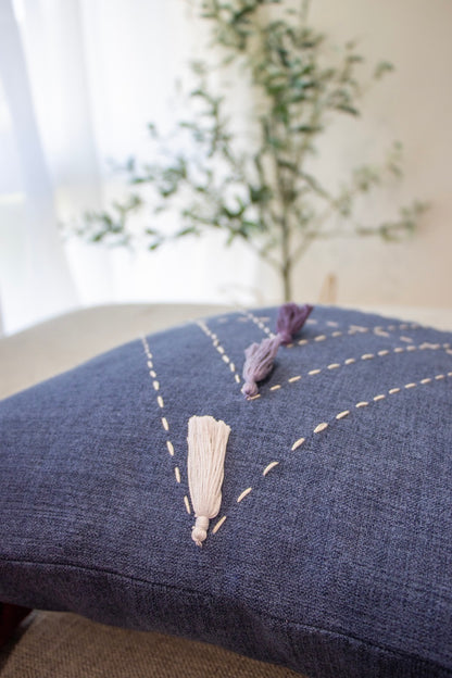 Close up of blue cushion cover with embroidery and tassels