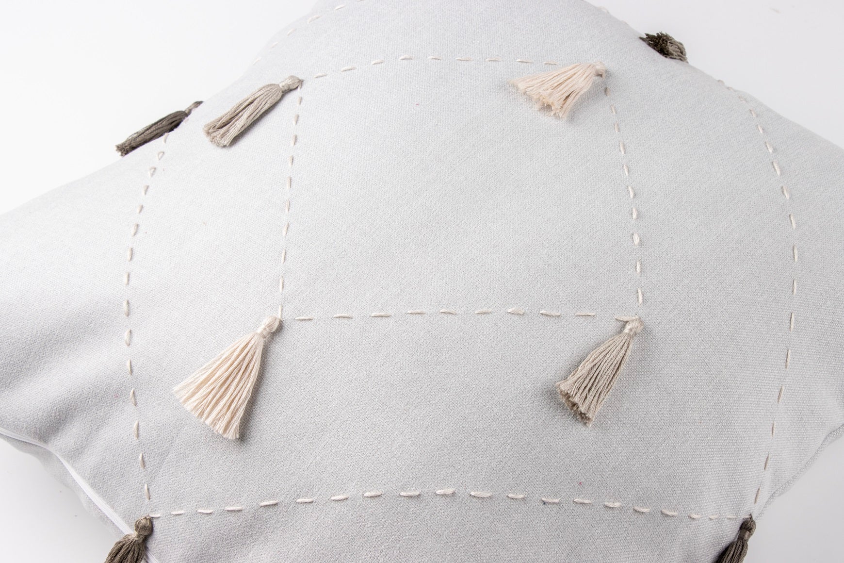 Close up of white diamond cushion cover with embroidery and tassels