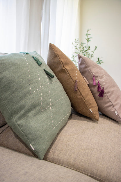 Brown, green and purple cushion cover with embroidery and tassels on couch