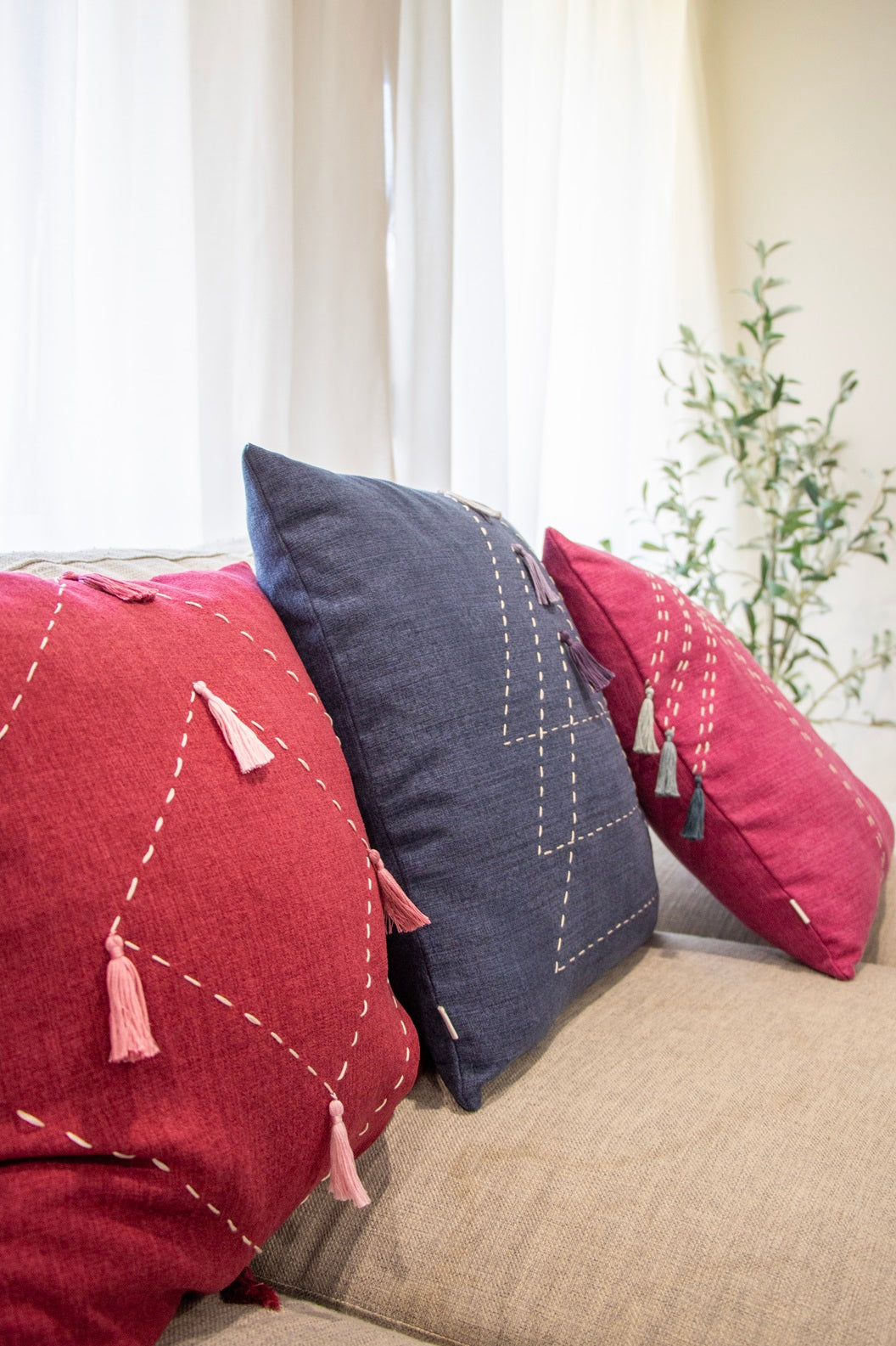 Bundle of pink and blue cushion cover with embroidery and tassels on couch