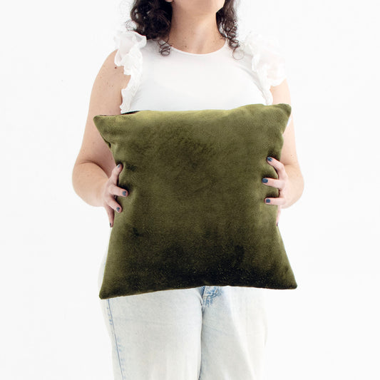 Person holding a green textured velvet cushion cover against a white background