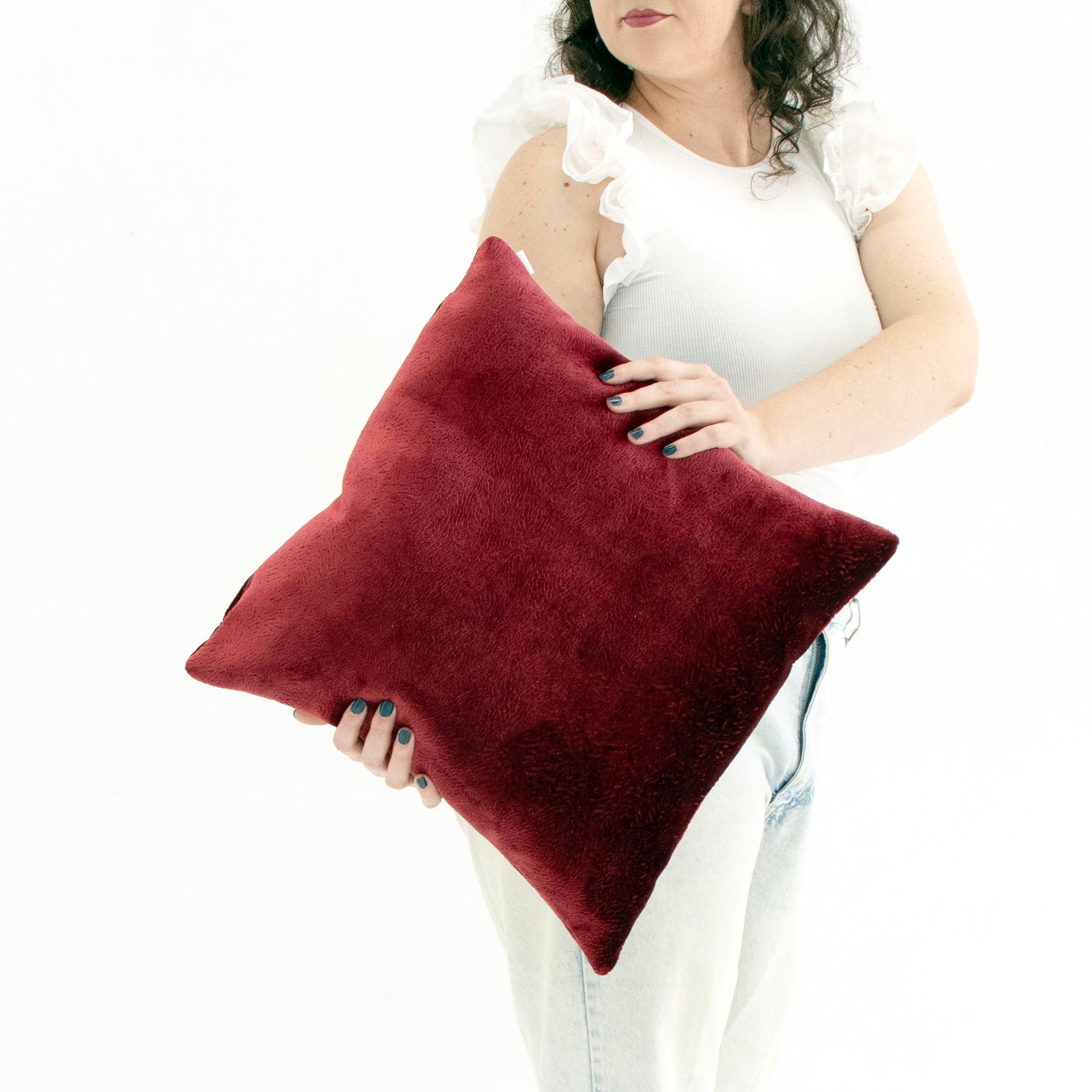 Person holding a red textured velvet cushion cover against a white background