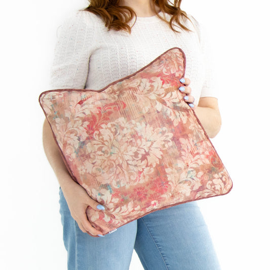 Person holding a floral cushion cover with piped edge against a white background