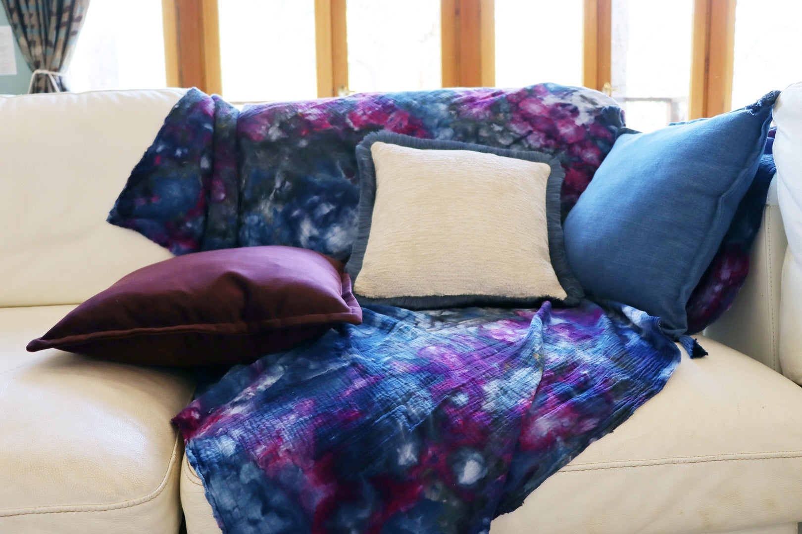 Colourful throw and chenille cushion cover with cotton fringe on a cream sofa