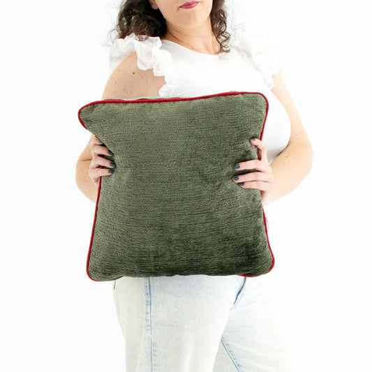 Person holding a green chenille cushion cover with contrasting piping against a white background