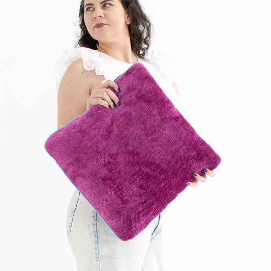 Woman holding a pink chenille cushion cover with contrasting piping against a white background