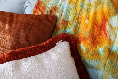 Close-up of a colourful throw with a chenille cushion cover with cotton fringe