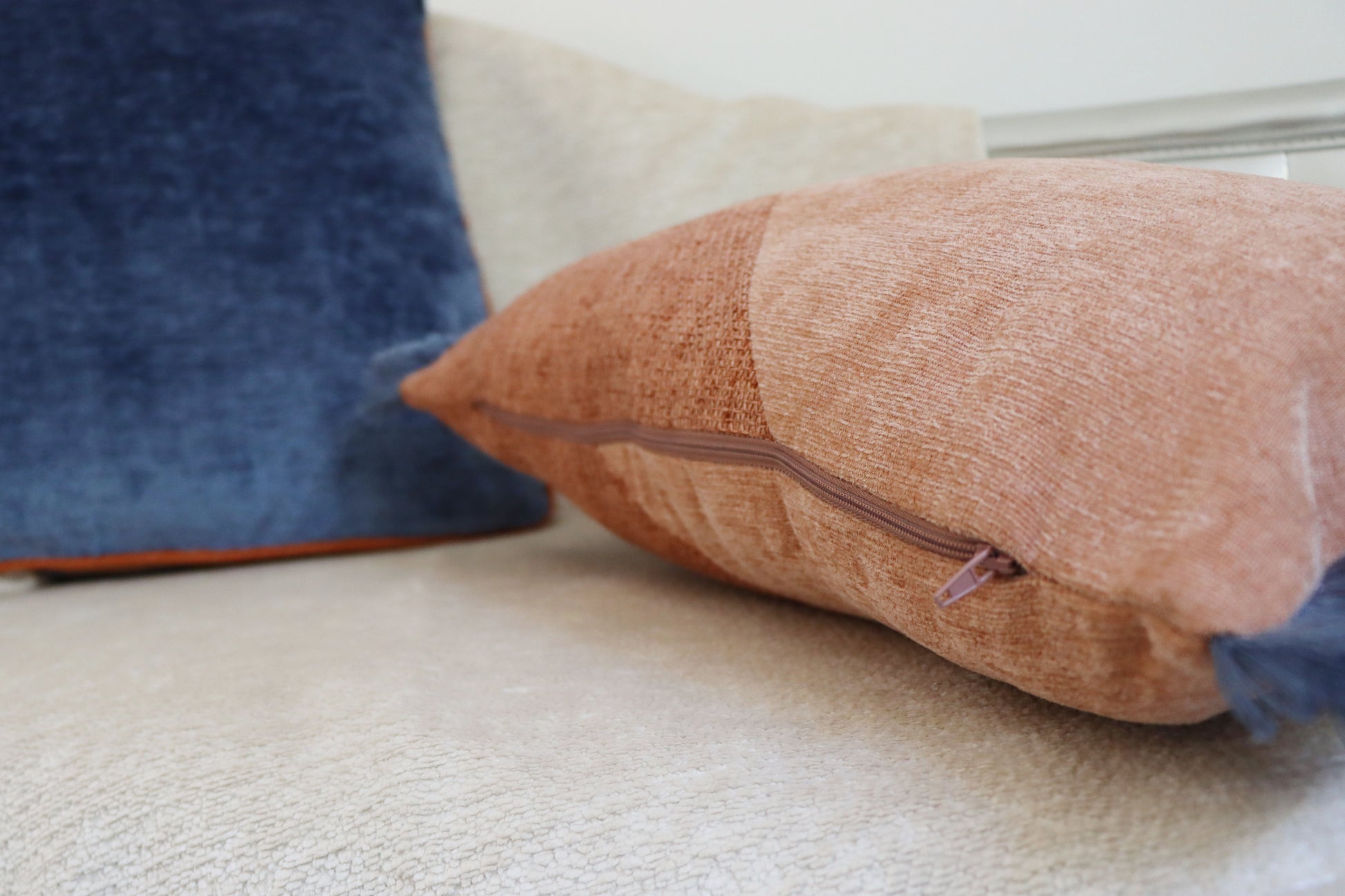 Close-up of an oblong cushion cover with cotton fringe zipper on a light surface