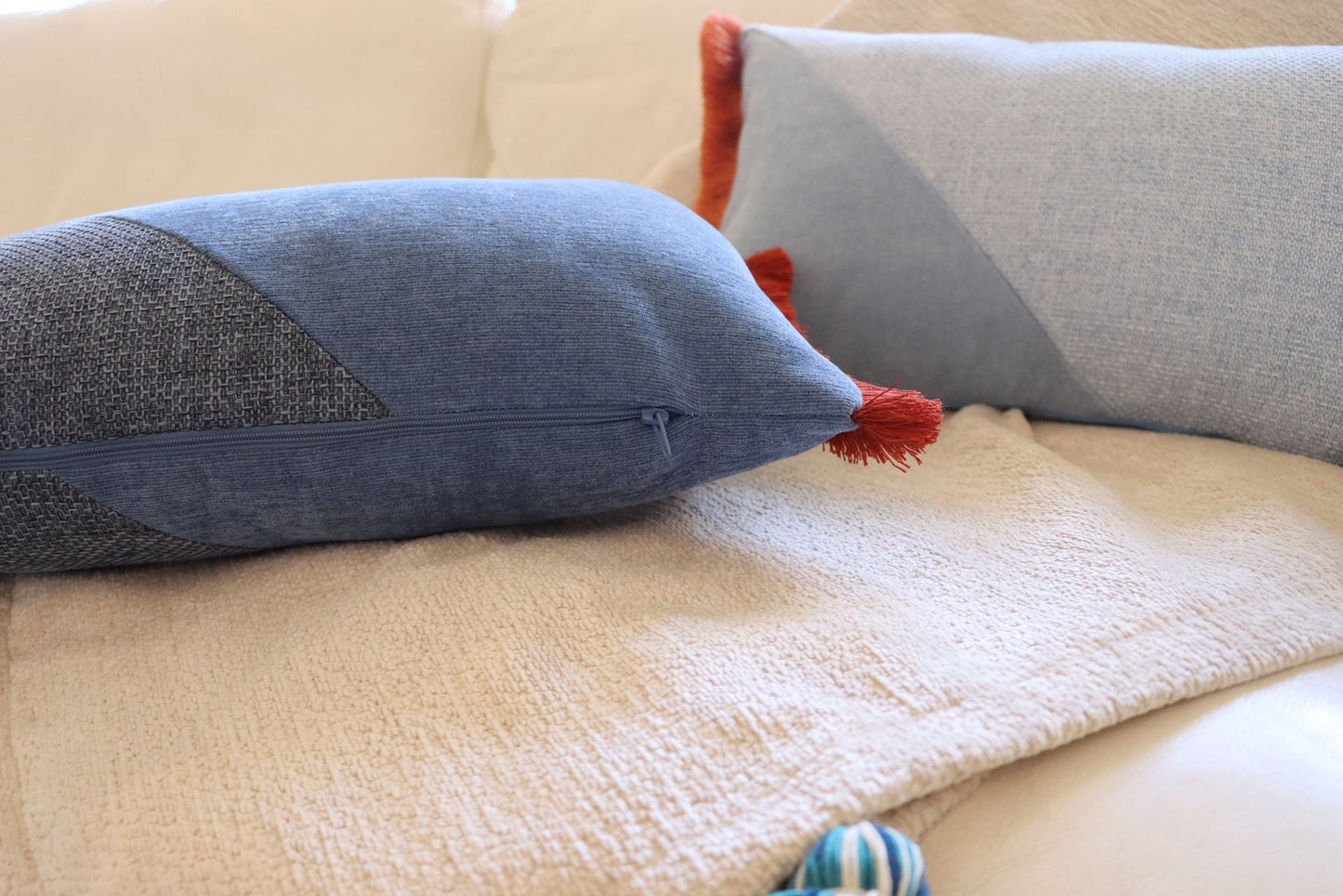 Close up of zipper of oblong cushion cover with cotton fringe