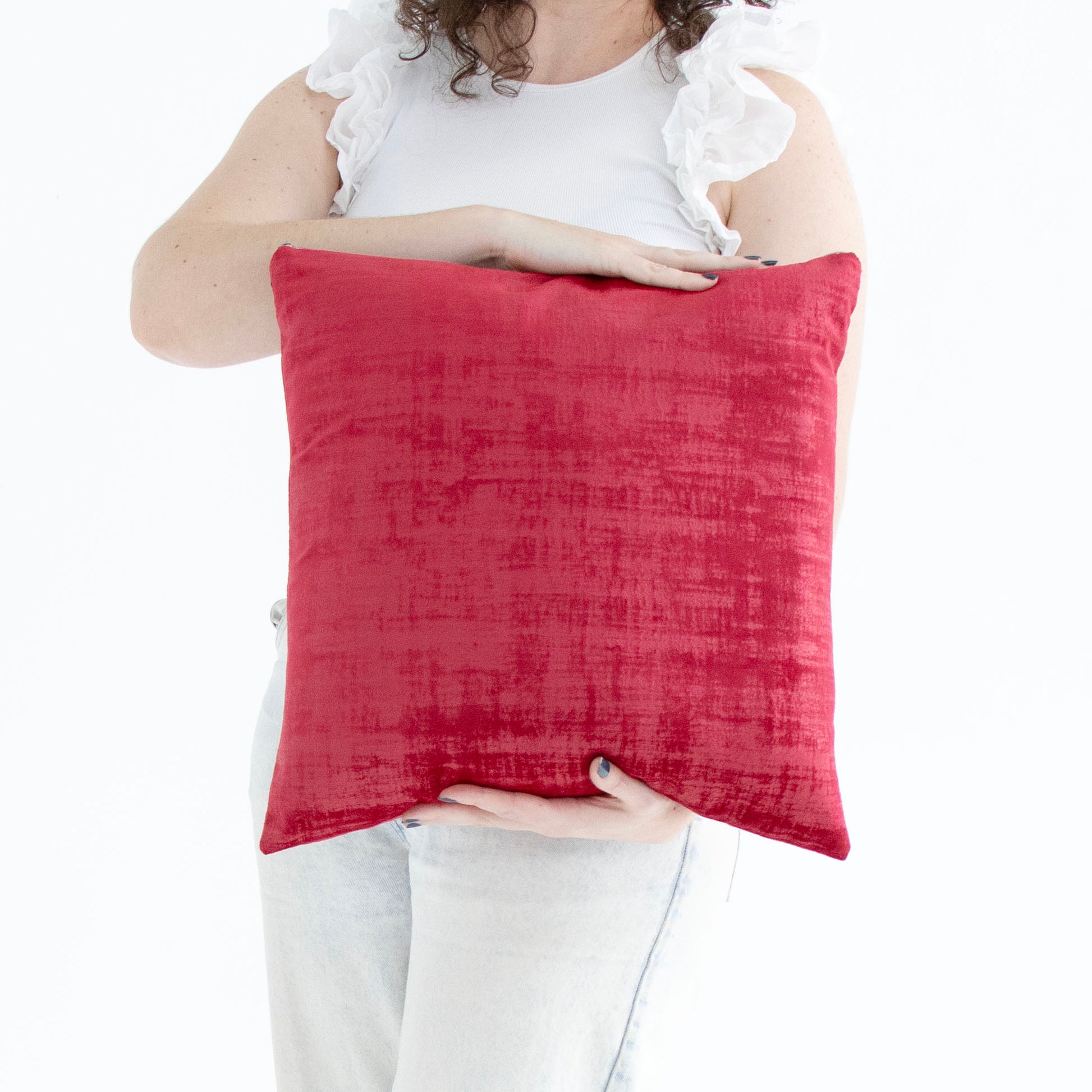 Person holding a red handmade textured velvet cushion cover with exposed zipper against a white background