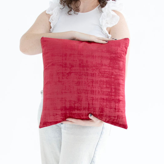 Person holding a red handmade textured velvet cushion cover with exposed zipper against a white background