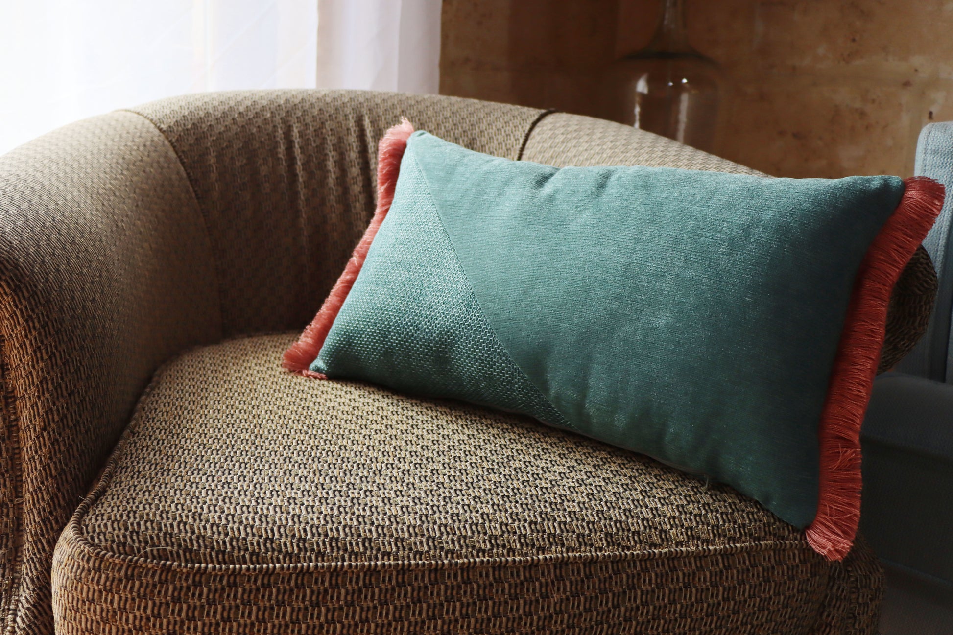 oblong cushion cover with cotton fringe on a brown textured chair