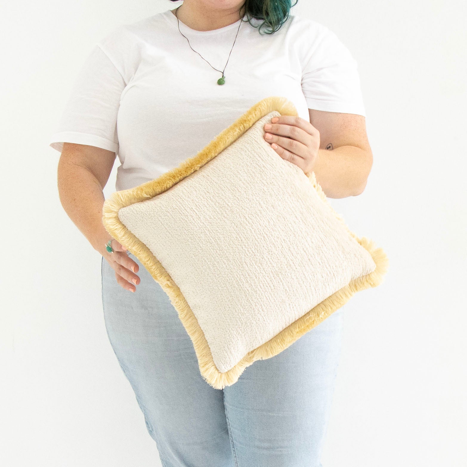 Person holding a textured chenille cushion cover with cotton fringe with a white background