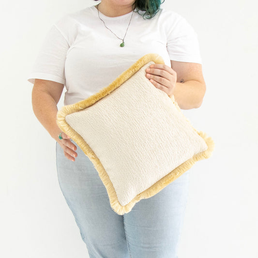 Person holding a textured chenille cushion cover with cotton fringe with a white background