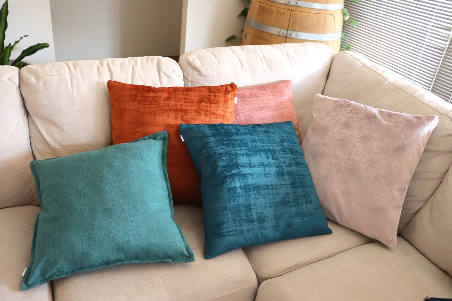 Lifestyle photo of pink and blue handmade textured velvet cushion cover with exposed zipper on sofa