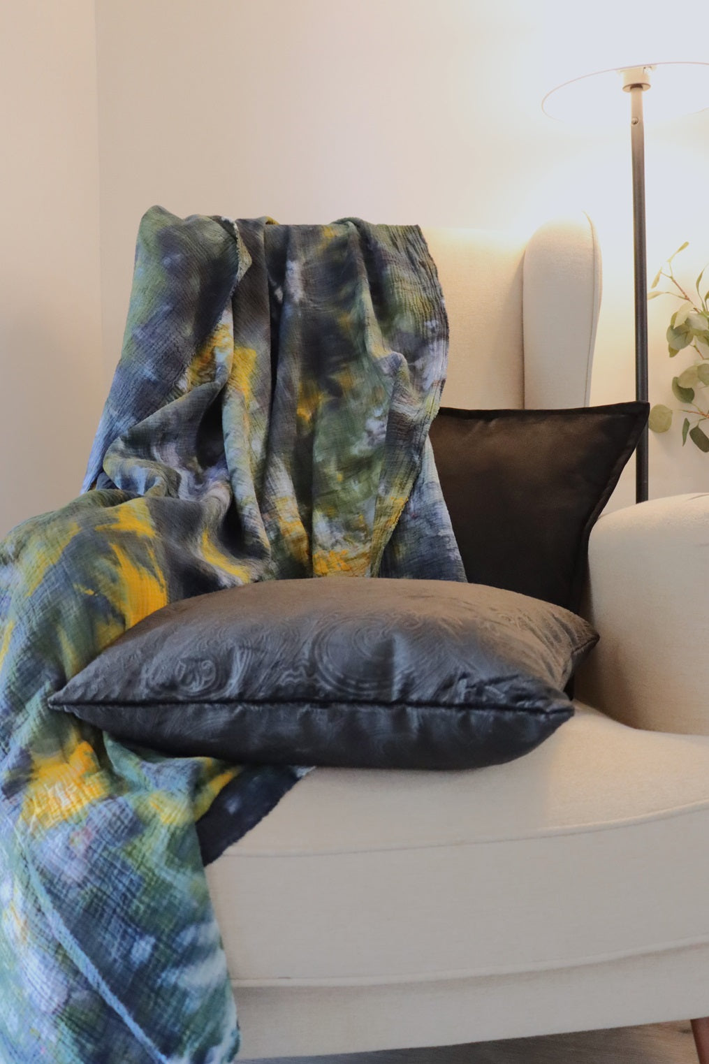 Lifestyle photo of green yellow black ice-dyed cotton throw