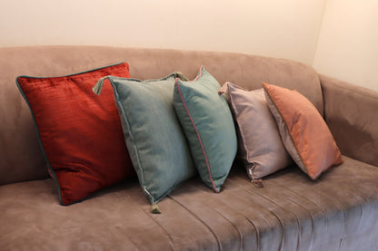 Lifestyle photo of handmade velvet cushion cover with contrasting piping on couch