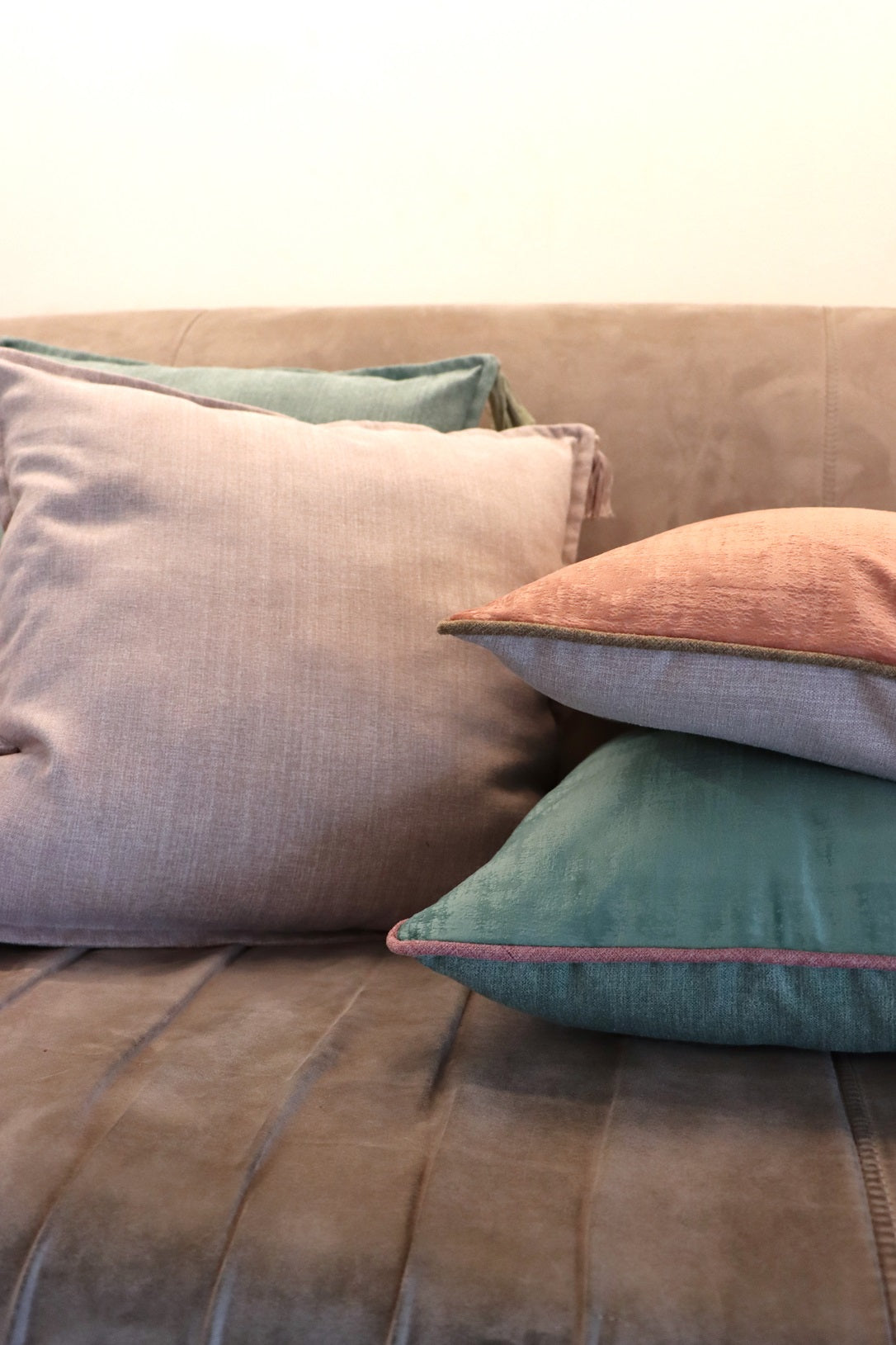 Lifestyle photo of pink and green high quality velvet cushion cover with contrasting piping on couch