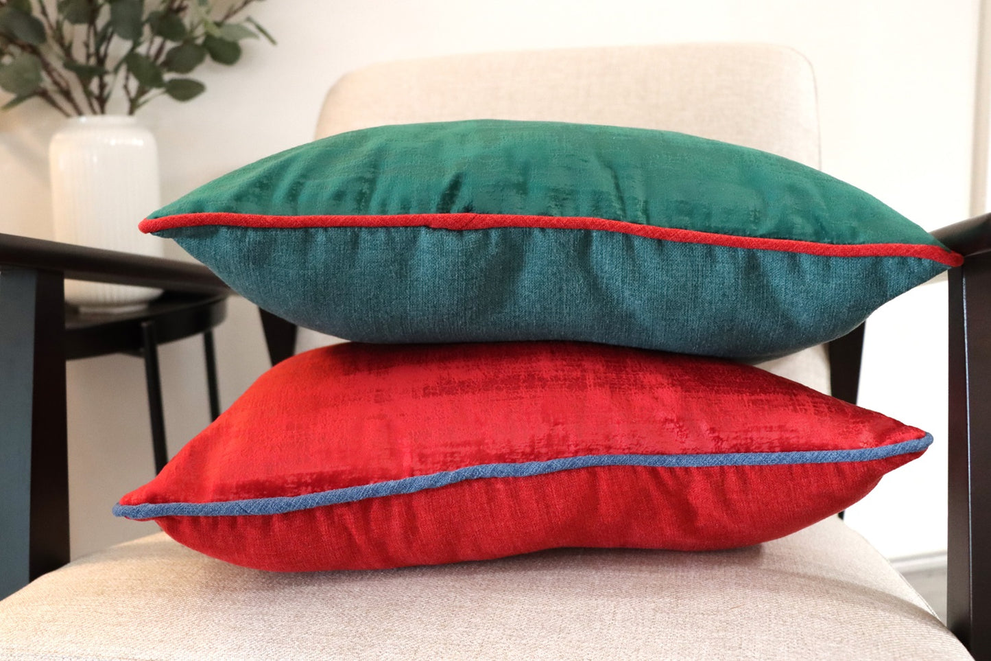 Stack of green and red Velvet Cushion Cover with Contrasting Piping on chair