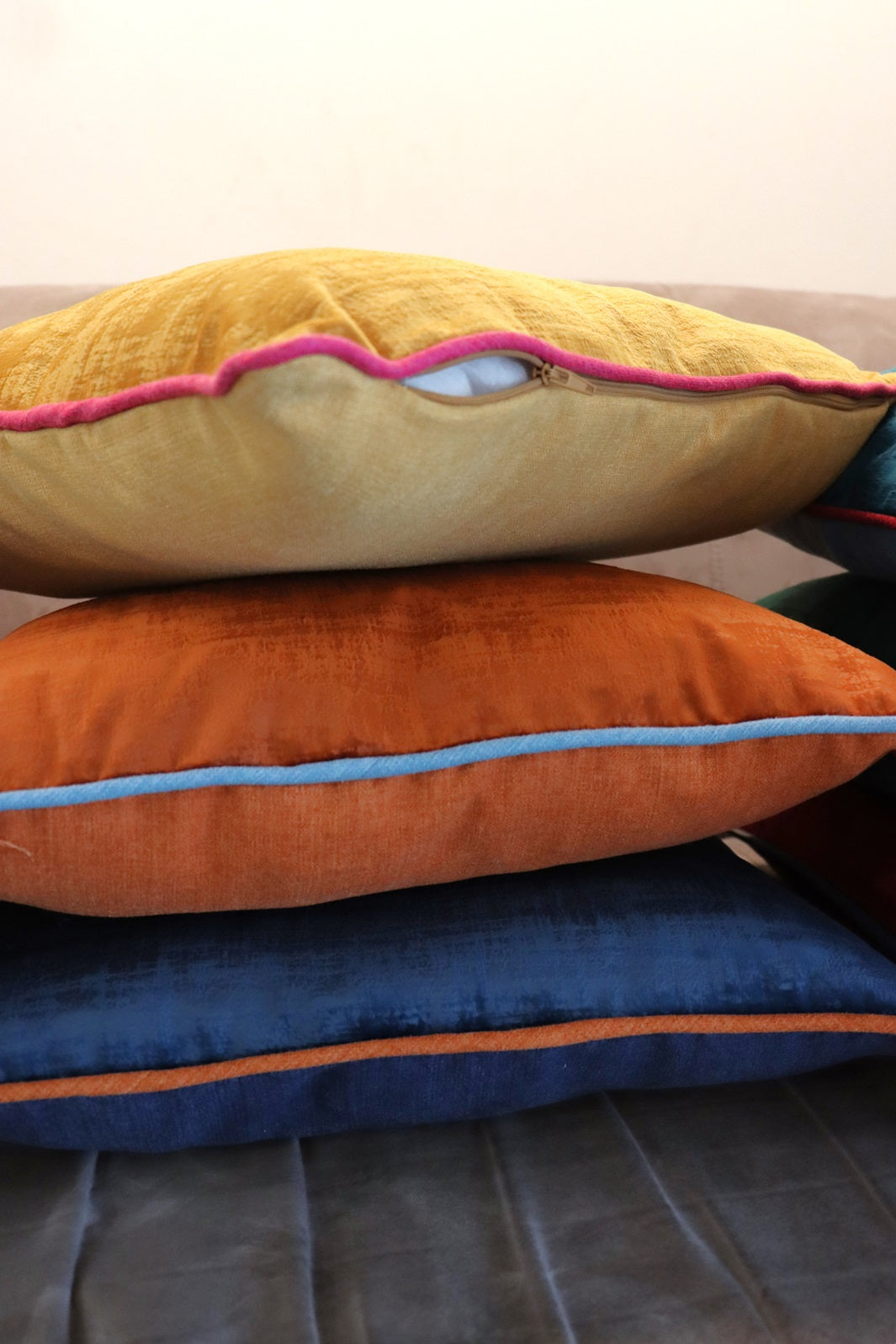 Stack of handmade velvet cushion cover with contrasting piping on couch