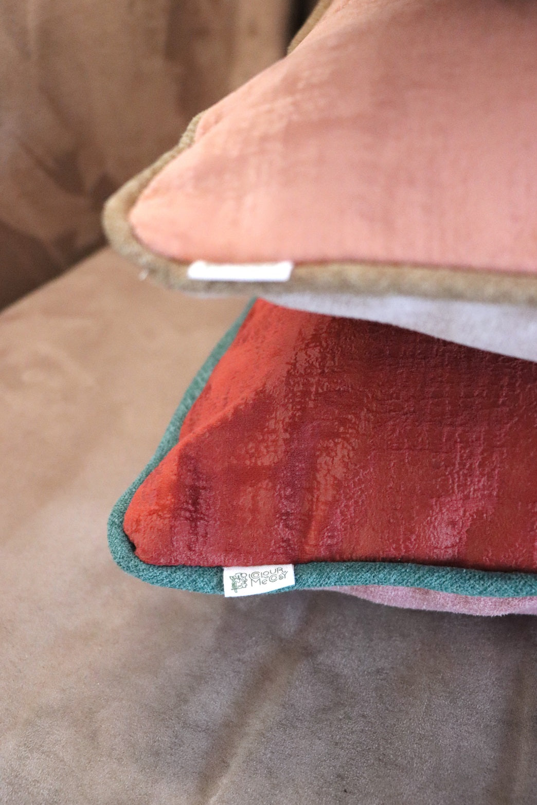 Close up of tag of handmade velvet cushion cover with contrasting piping on sofa