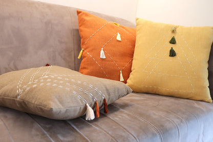 Lifestyle photo of handmade cushion cover with embroidery and tassels on couch