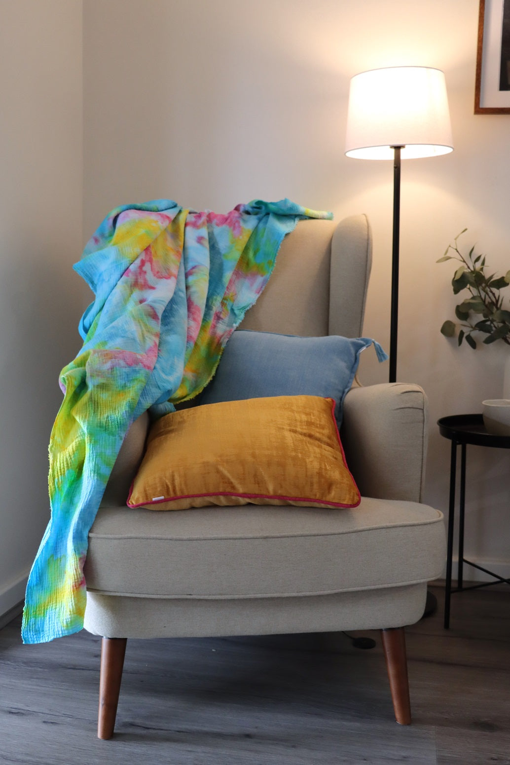 Lifestyle photo of yellow, pink and blue ice-dyed cotton throw on couch