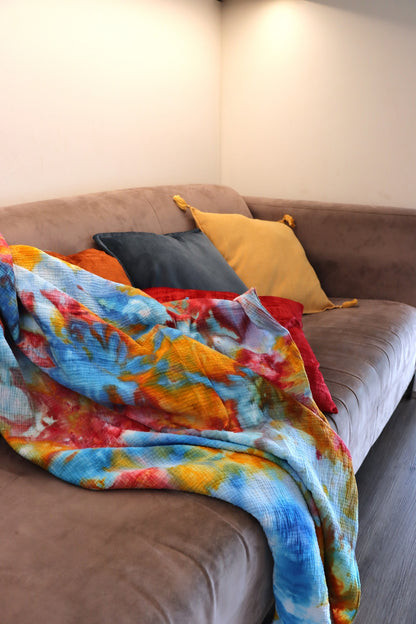 Folded red, yellow and blue ice-dyed cotton throw on couch