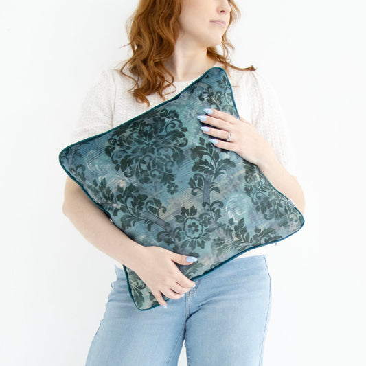 Woman holding a blue floral cushion cover with piped edge on a white background