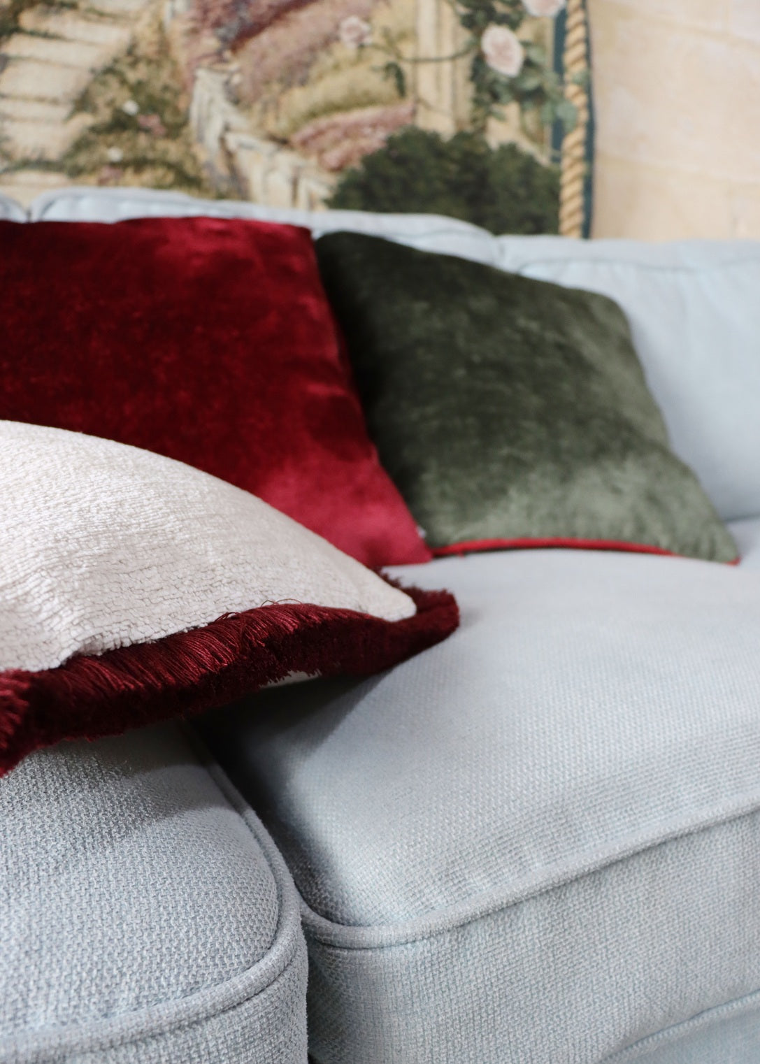 Gray sofa with colorful cushions including red textured velvet cushion cover.