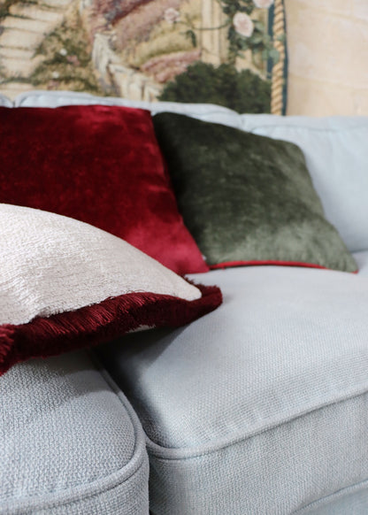 Gray sofa with colourful chenille cushion cover with cotton fringe including red, white, and green.