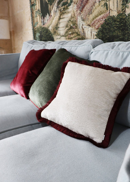 Gray sofa with chenille cushion cover with cotton fringe in a room with decorative elements.