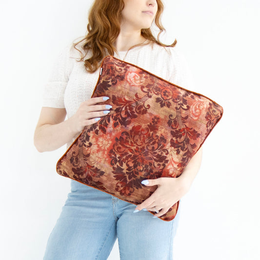 Person holding a floral cushion cover with piped edge against a white background