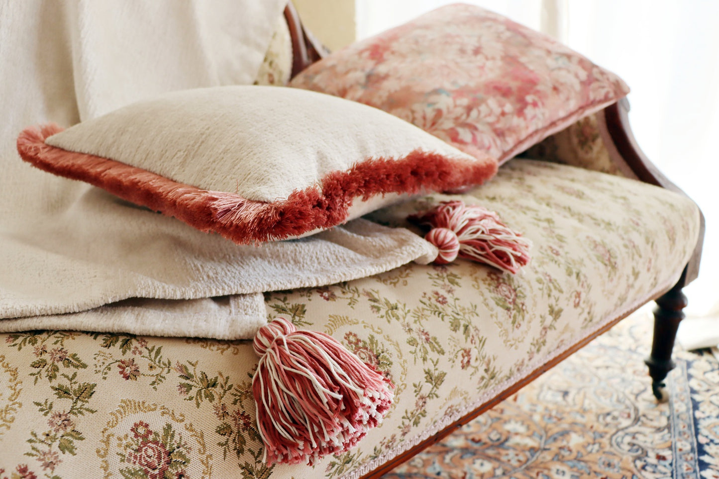 Floral-patterned sofa with decorative pink chenille cushion cover with cotton fringe