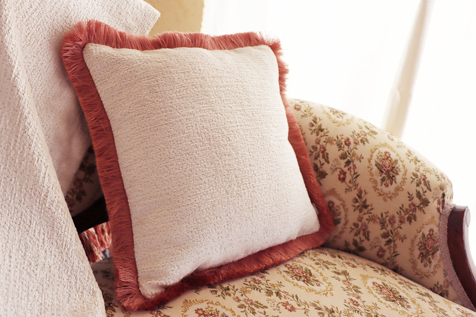 Decorative chenille cushion cover with cotton fringe on a floral-patterned sofa