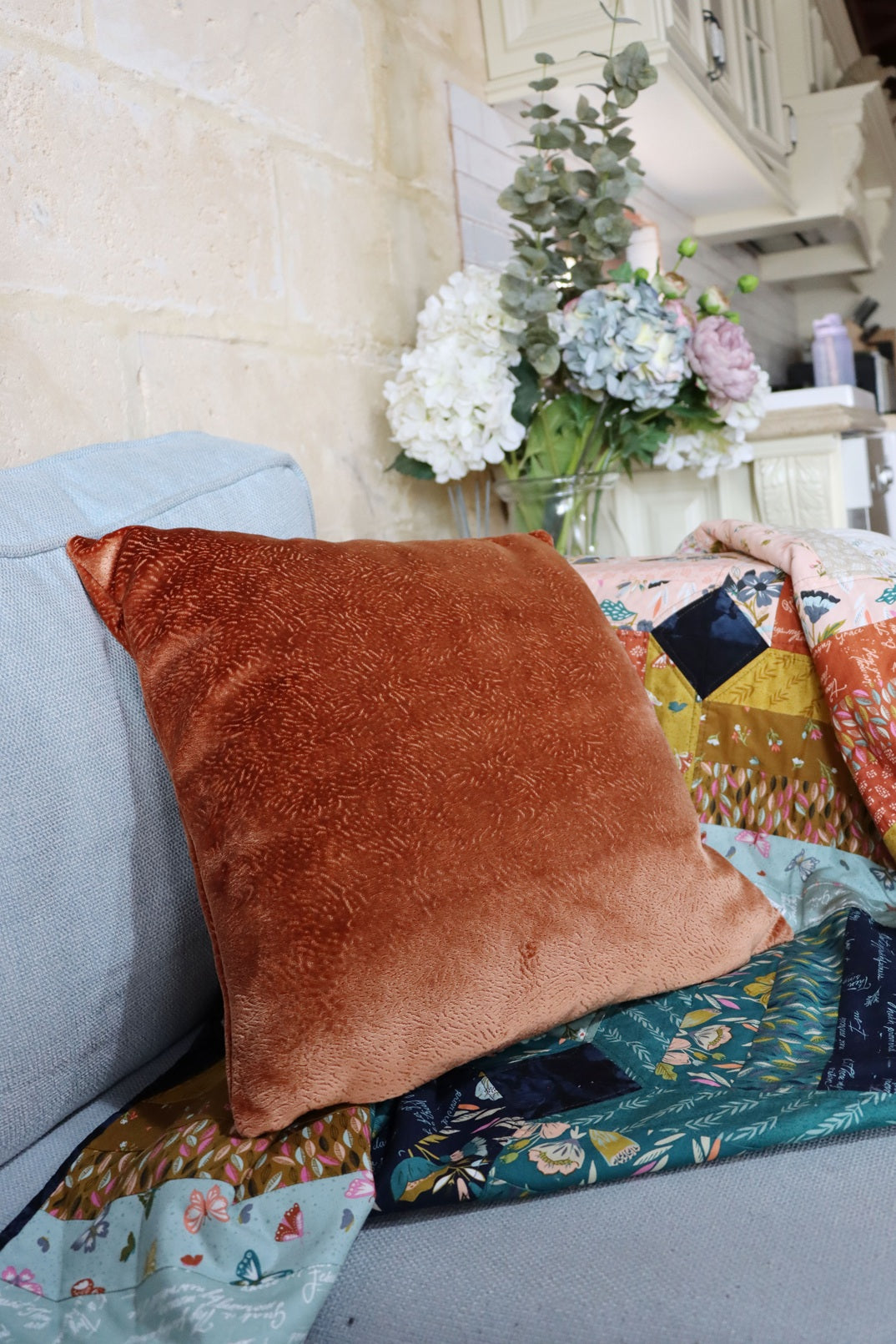 textured velvet cushion cover on a sofa with a decorative plant in the background